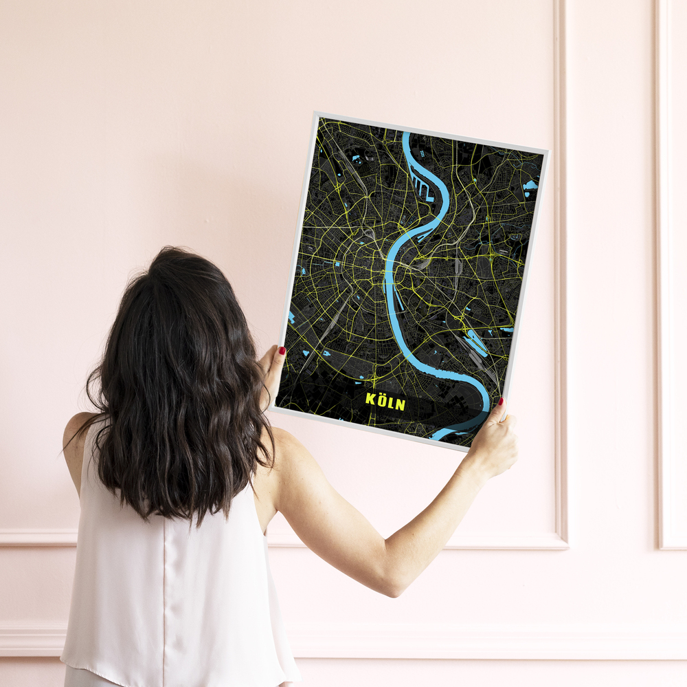 Poster della mappa di Colonia con bordo bianco, Reno turchese e strade giallo neon davanti a una parete rosa chiaro