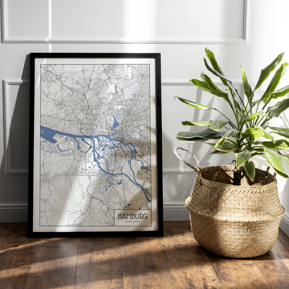 Mappa di Amburgo in stile architettonico con cornice nera, a terra accanto a una pianta in un cesto