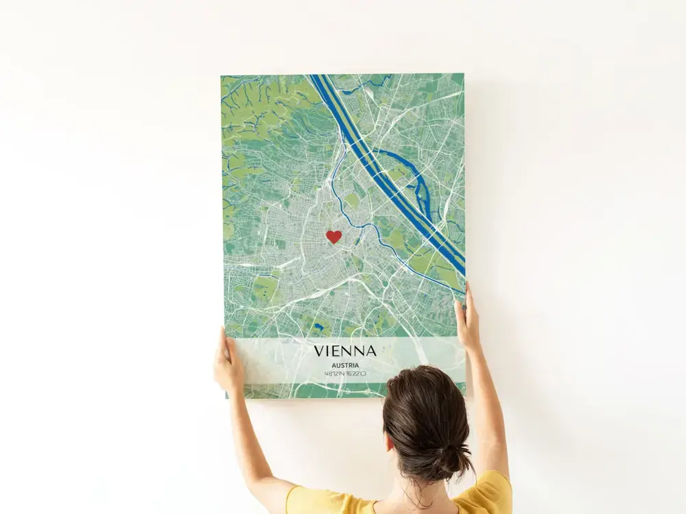 Poster con mappa urbana verde e blu, cuore e coordinate su fascia chiara, su una parete bianca