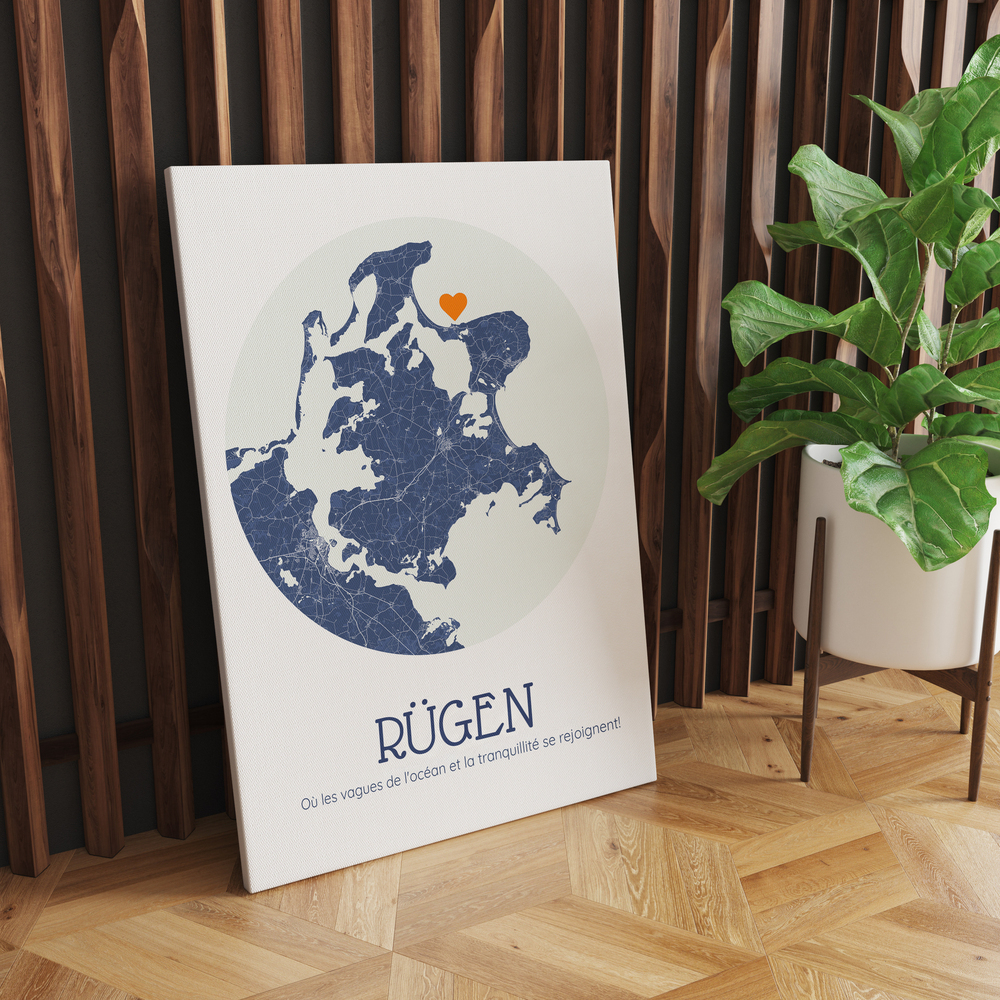 Tableau avec carte ronde de Rügen en bleu et cœur orange, posé au sol contre des lattes de bois près d’une plante